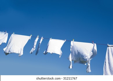 White Clothes Hanging On The Line Against Blue Sky.