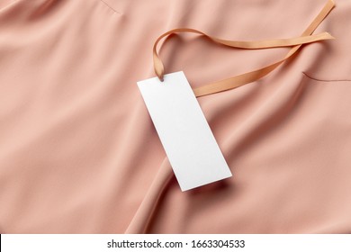 White Clothing Tag, Label Blank Mockup Template With The Ribbon, To Place Your Design. On A Premium Cotton Pink Fabric Textile Background