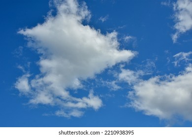 White Clouds Against Blue Sky For A Backgrounds. Puffy Fluffy White Clouds Against Daytime Sky. Cumulus Is A Fluffy Cloud Like A Cotton Ball