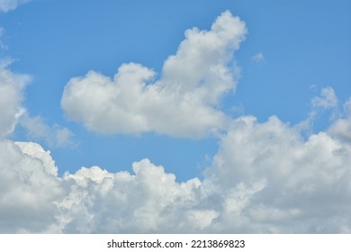 White Clouds Against Blue Sky For A Backgrounds. Puffy Fluffy White Clouds Against Daytime Sky. Cumulus Is A Fluffy Cloud Like A Cotton Ball