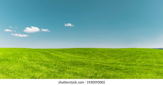 White clouds in blue sky over green meadow