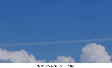 White clouds forming thin linear streaks across a blue sky. Minimal and natural sky background suitable for design projects, abstract compositions, nature themes, weather concepts, and clean visual layout