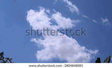 White clouds in the shape of a dinosaur or dragon in the blue sky on a sunny day.