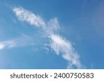 White clouds in the shape of a flying bird or a cross in the sky.