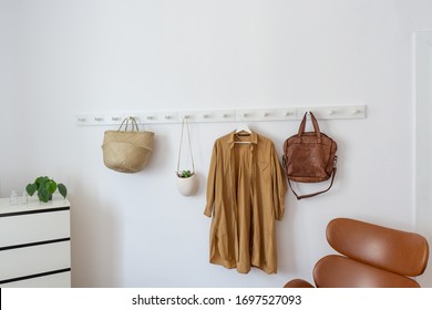 White coat-rack with basket, plant, coat and armchair - Powered by Shutterstock