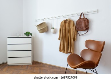 White coat-rack with basket, plant, coat and armchair - Powered by Shutterstock