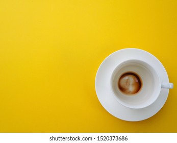 The White Coffe Cup Has Stained Coffee, The Bottom Of The Cup Is On The Yellow Floor With A Space For Text.