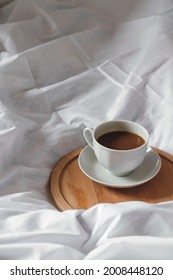 White coffee cup on bed. Cozy autumn morning photography. Still life concept. White fabric background. 