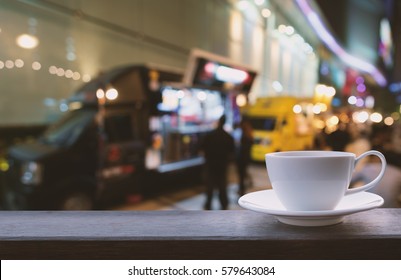 White coffee cup on brown timber with blurred of food trucks and bokeh lights background - Powered by Shutterstock