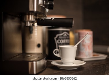 White Coffee Cup With Saucer On Kitchen Table With Modern Coffee Machine. Modern Coffee Station At Home