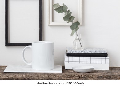 White coffee mug mockup, rustic wood shelf, empty frames and notebooks