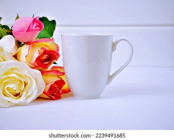 White coffee mug mockup with s bouquet of rose flowers on a white table background ,Blank copy space for text or design Valentine's Day concept Empty mug mock up Template layout Advertising 