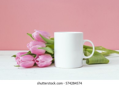 White coffee mug with pink tulips on a pink background. Space for text or design. Valentine's Day Concept.