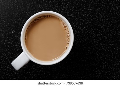 White Coffee Or Tea With Bubbles In White Ceramic Mug Isolated On Black Granite Table From Above.