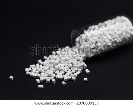 White cold cut masterbatch granules with glass tubes isolated on a black background, this material is a colorant for products in the plastics industry