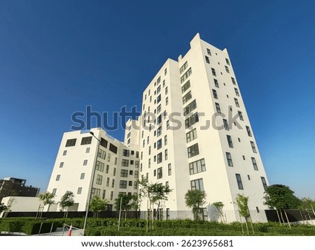 White Color Commercial Residential Building Complex with Black Color Windows And Blue Sky Background. Highrise Skyscraper Building Exterior Outdoor Full View. G+10 floor Tallest Skyline With PentHouse