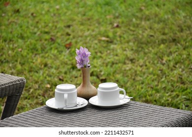 White Color Porcelain Tea Cups Kept Before Outdoor High Tea Table In The Garden Blurry Background