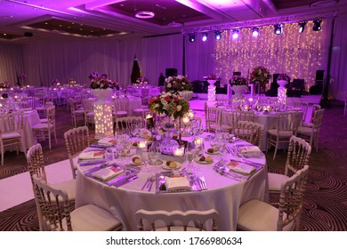 White color wedding table decorated with decorative and elegant for wedding. There are flowers, candles and serving plates on the wedding table.
