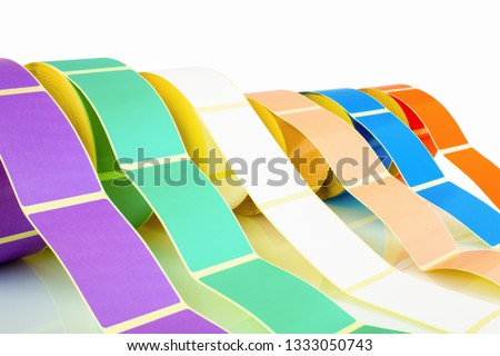 White and colored label rolls isolated on white background with shadow reflection. Color reels of labels for printers. Labels for direct thermal or thermal transfer printing. Close shot of stickers.