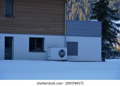 White colour air source heat pump installed outside the family house in winter for heating and cooling homes. Equipment work by moving outdoor heat indoors, or vice versa.