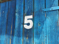 White Colour Number Five On An Old Abandoned Blue Colour Wooden Gate In Budapest Suburb, Hungary