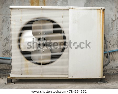 White Com Air air conditioner is placed outside the building to rust.