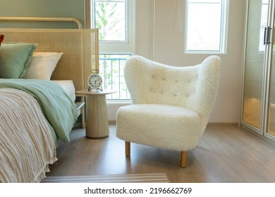 White Comfy Armchair Standing Near Cozy Bed With Cushions, Pillows And Bedding. 