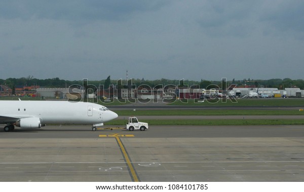 White commercial aircraft\
airplane pulled/towed by little white car on the runway of an\
airport