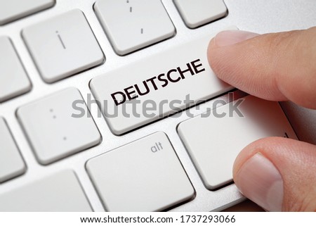 White computer keyboard and blue button against Deutsche background.Male hand pressing Deutsche written button on computer keyboard.
