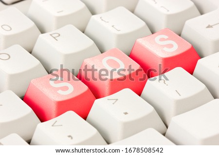 White computer keyboard with red keys arranged in the word SOS. Computer keyboard with SOS keys.