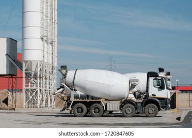 White concrete mixer standing by a modern concrete plant.