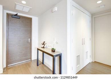 White Condo Entrance Hall Features Console Table Atop Light Brown Hardwood Floor. Northwest, USA