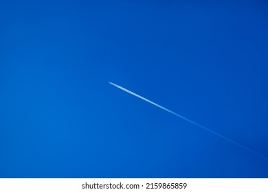 A white contrail in cloudless blue sky