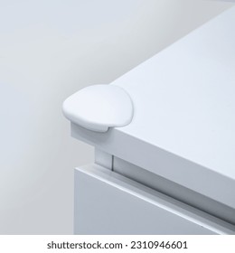 White corner bumper guard at the cabinet angle. Protect children from sharp part of furniture. - Shutterstock ID 2310946601