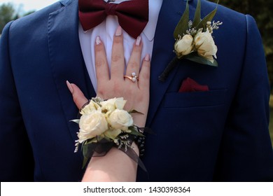 White Corsage And Boutonnière With Fancy Nails On Blue Tuxedo With Red Bow Tie For High School Senior Prom