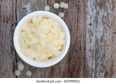 White Cosmetic Beeswax Pellets In White Bowl On Wooden Background.
