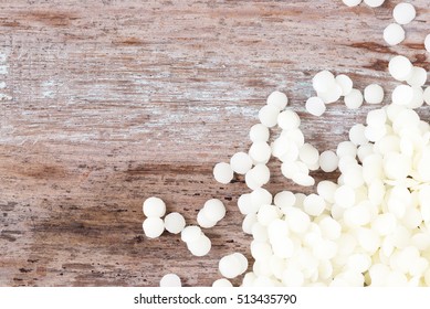 White Cosmetic Beeswax Pellets On Wooden Background.
