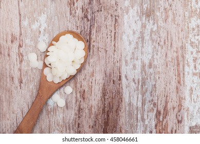 White Cosmetic Beeswax Pellets In Wooden Spoon. 
