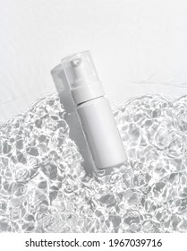 White cosmetic bottle on the water surface. Blank label for branding mock-up. Flat lay, top view.