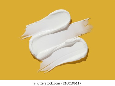 White cosmetic cream lotion swatch smear smudge on yellow color background.	
