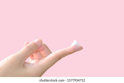 White Cosmetic Cream On Finger Tip Isolated On Pastel Pink Background. Concept For Skin Beauty Tips And Skin Care.