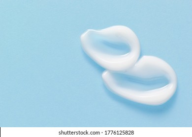 White Cosmetic Cream Smears On Pastel Blue Background. Skincare Lotion Face Serum Swatch. Beauty Product Sample Closeup