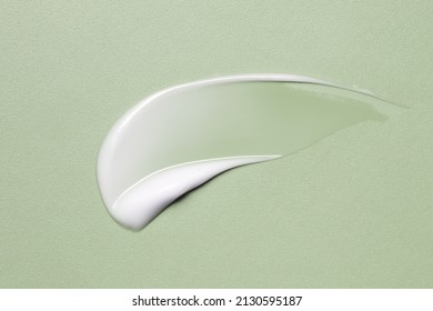 White cosmetic cream texture, skincare lotion swatch on green. Face creme, body moisturiser, hair conditioner smear smudge stroke on color background. Creamy beauty product closeup