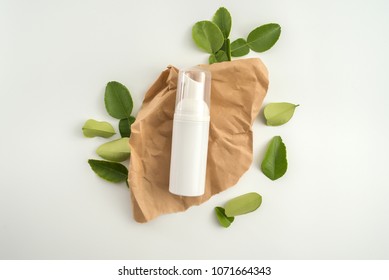 White Cosmetic Products And Green Leaves On White Background. Natural Beauty Blank Label For Branding Mockup Concept.