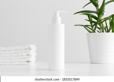 White Cosmetic Shampoo Dispenser Bottle Mockup With A Aloe Vera And Towels On A White Table.