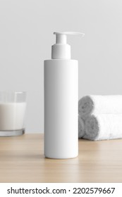 White Cosmetic Shampoo Dispenser Bottle Mockup With A Candle And Towels On The Wooden Table.