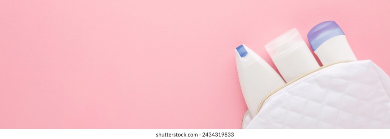 White cosmetic travel bag with plastic bottles on pink table background. Pastel color. Care about clean and body skin. Female beauty products. Closeup. Wide banner. Empty place for text. Top view.
