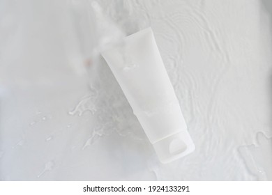 White Cosmetic Tube For Face Cream, Hand Cream, Body Lotion Or Face Cleanser On Light Blue Background With Water. Moisturizing Cosmetic Product Concept. Copy Space