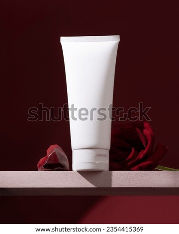 White cosmetic tube is gracefully displayed on a pedestal, adorned with vibrant red roses and a heart on the sides