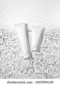 White cosmetic tubes on the water surface. Blank label for branding mock-up. Summer water pool fresh concept. Flat lay, top view.